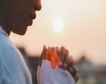 Woman praying in the morning on the sunrise background. Christianity concept. Pray background. Faith hope love concept.